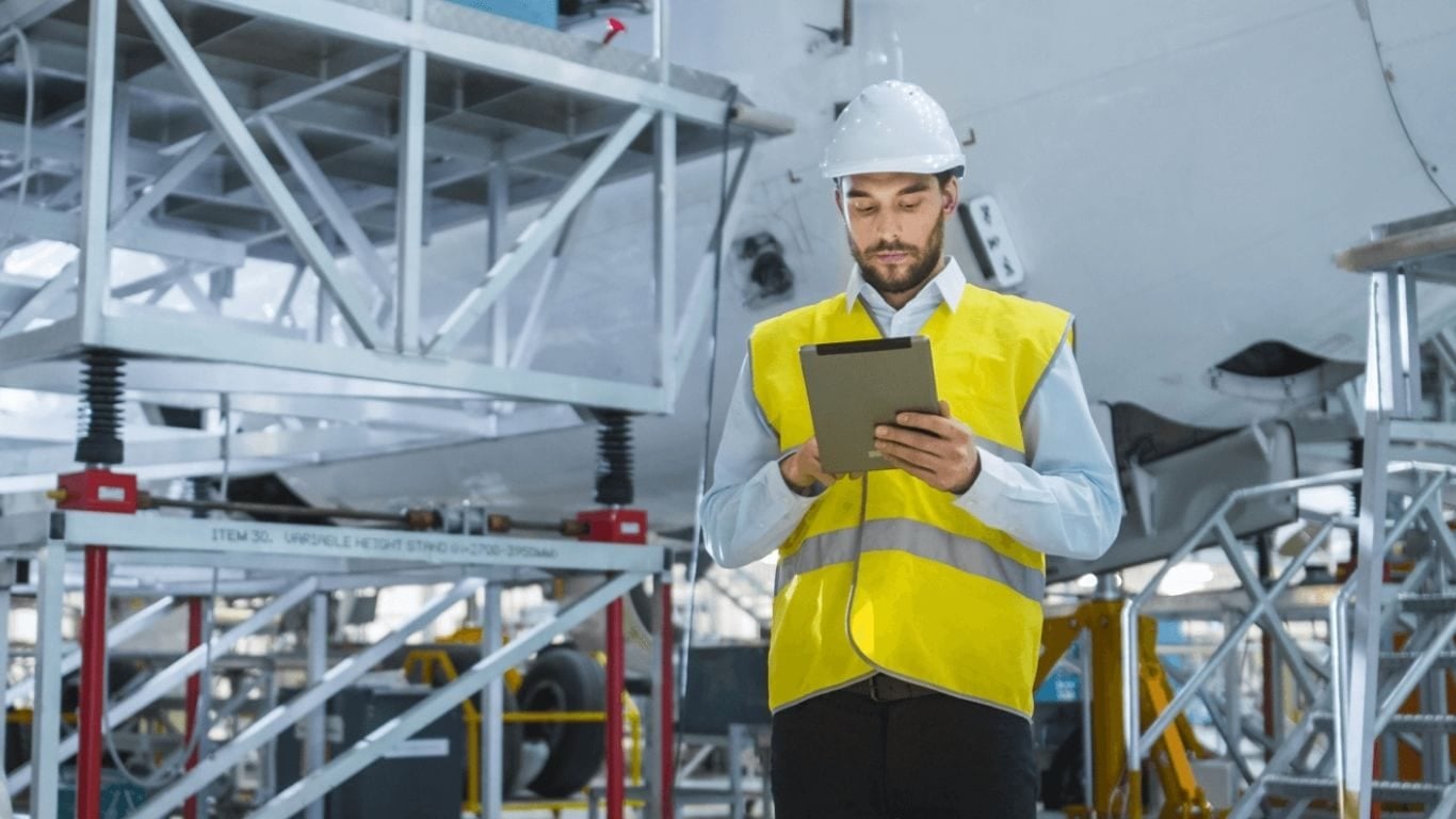 man in hard hat and high vis looking at tablet device
