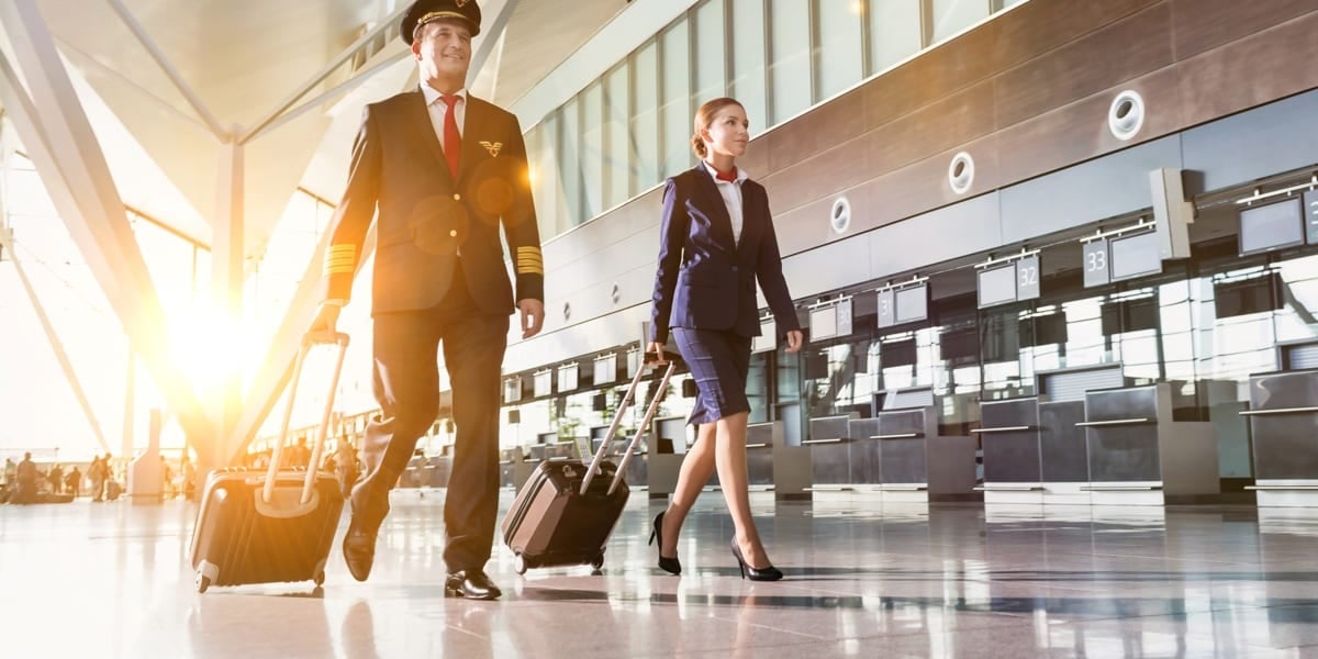 Pilot and air hostess walking with suitcases in airport
