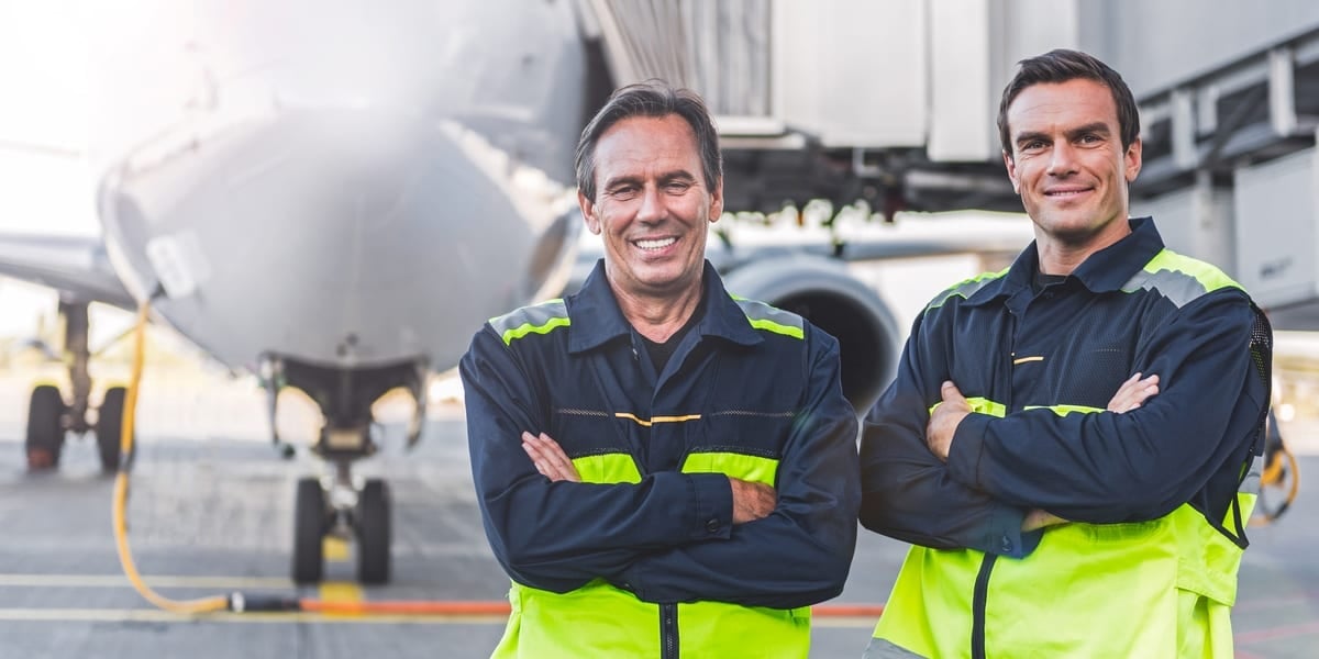 two men in high vis in front of aeroplane