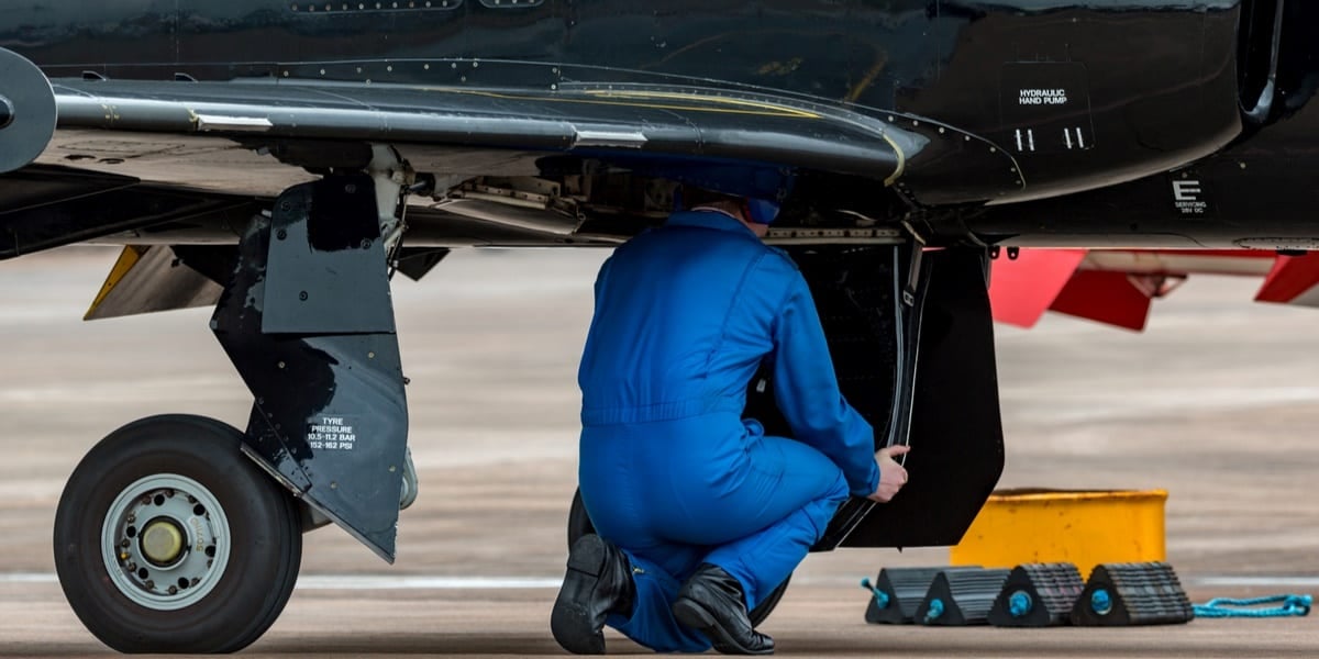 man in blue jumpsuit inspecting aeroplane