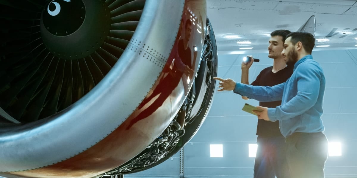 two men looking at an aeroplane engine
